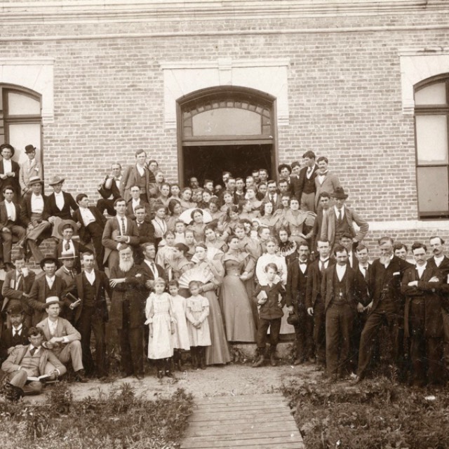 A group of students and faculty gathers for a photo in front of one of the buildings of AddRan Christian University in 1895