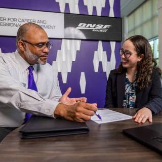 Female career center professional with pen and paper interviewing a student