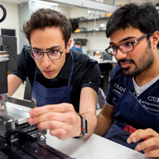 Two male students looking intently at a lab instrument