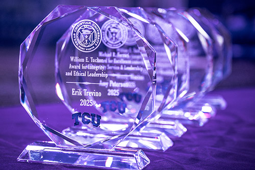 Several award trophies sit on a table, awaiting the announcement of each recipient.