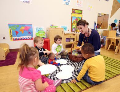 A teacher sits with her students in a classroom.