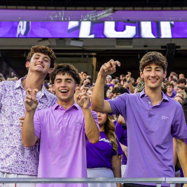 Image of three TCU male students in the stands at Amon G. Carter Stadium