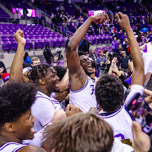 TCU basketball players and fans celebrate on the court of Schollmaier Arena